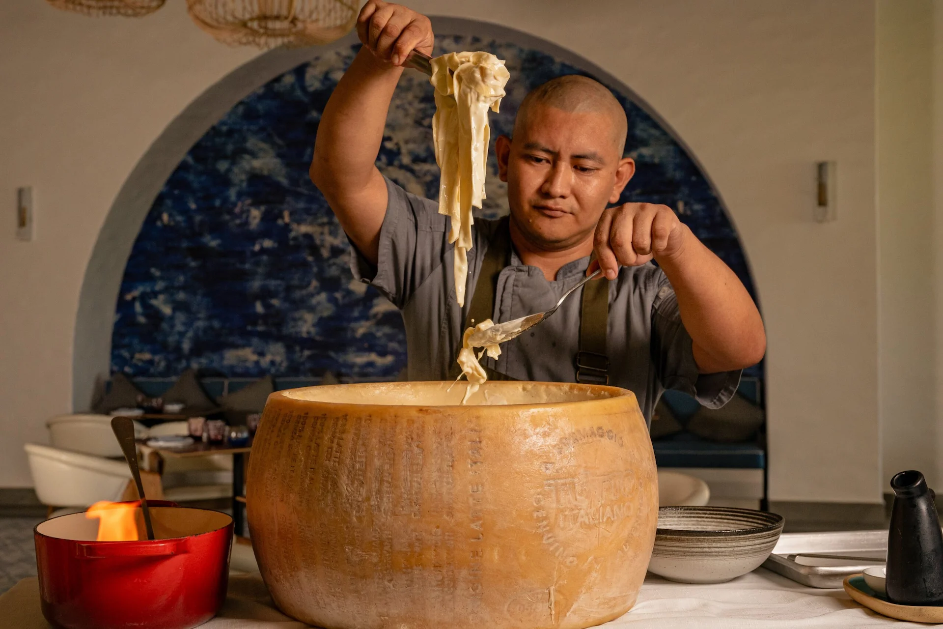 Chef preparing pasta in a Parmigiano wheel at Maratea restaurant at the Conrad Tulum Riviera Maya resort.