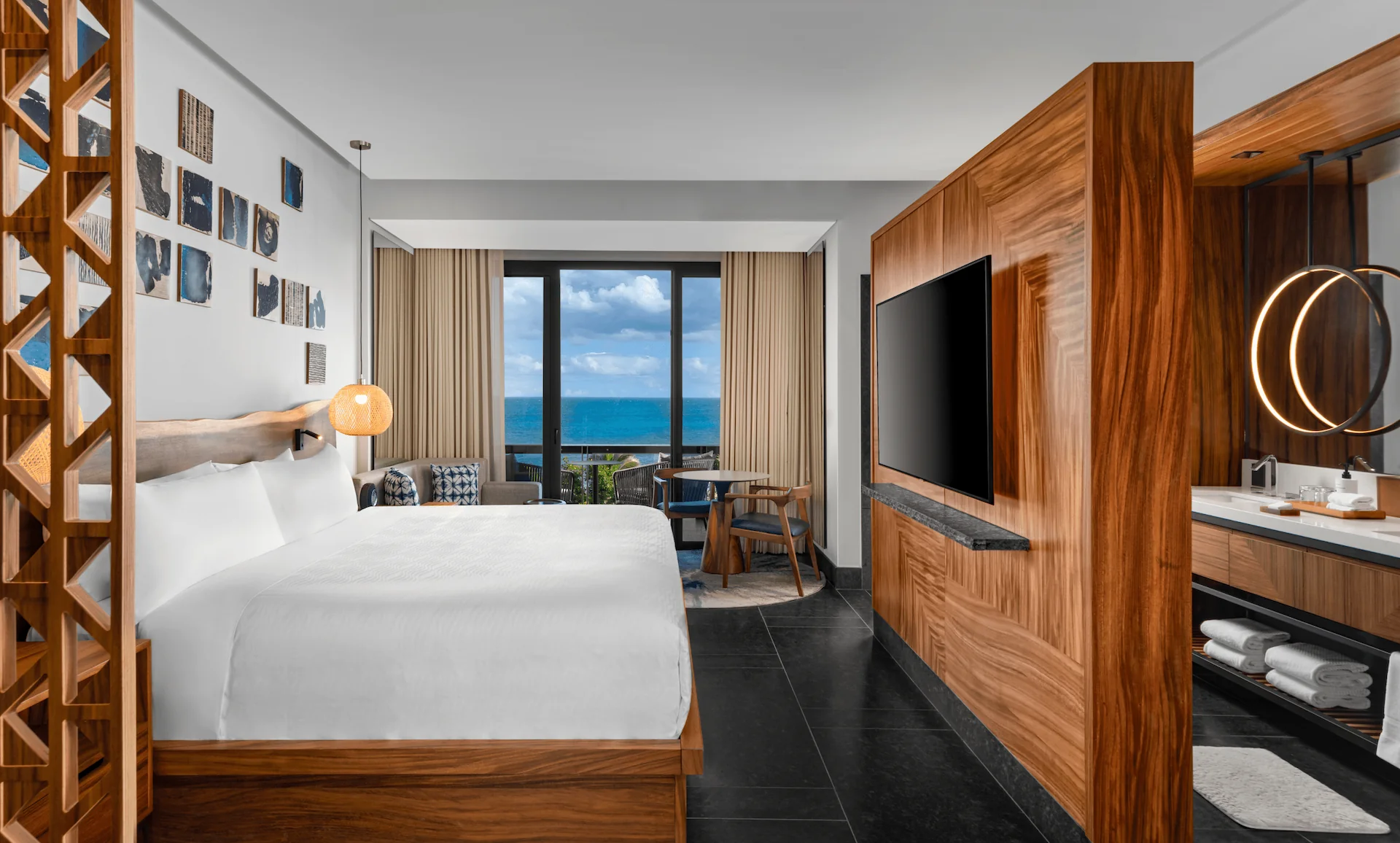 Elegant guestroom with king bed, ocean view, floor-to-ceiling windows, and private terrace at Conrad Tulum.