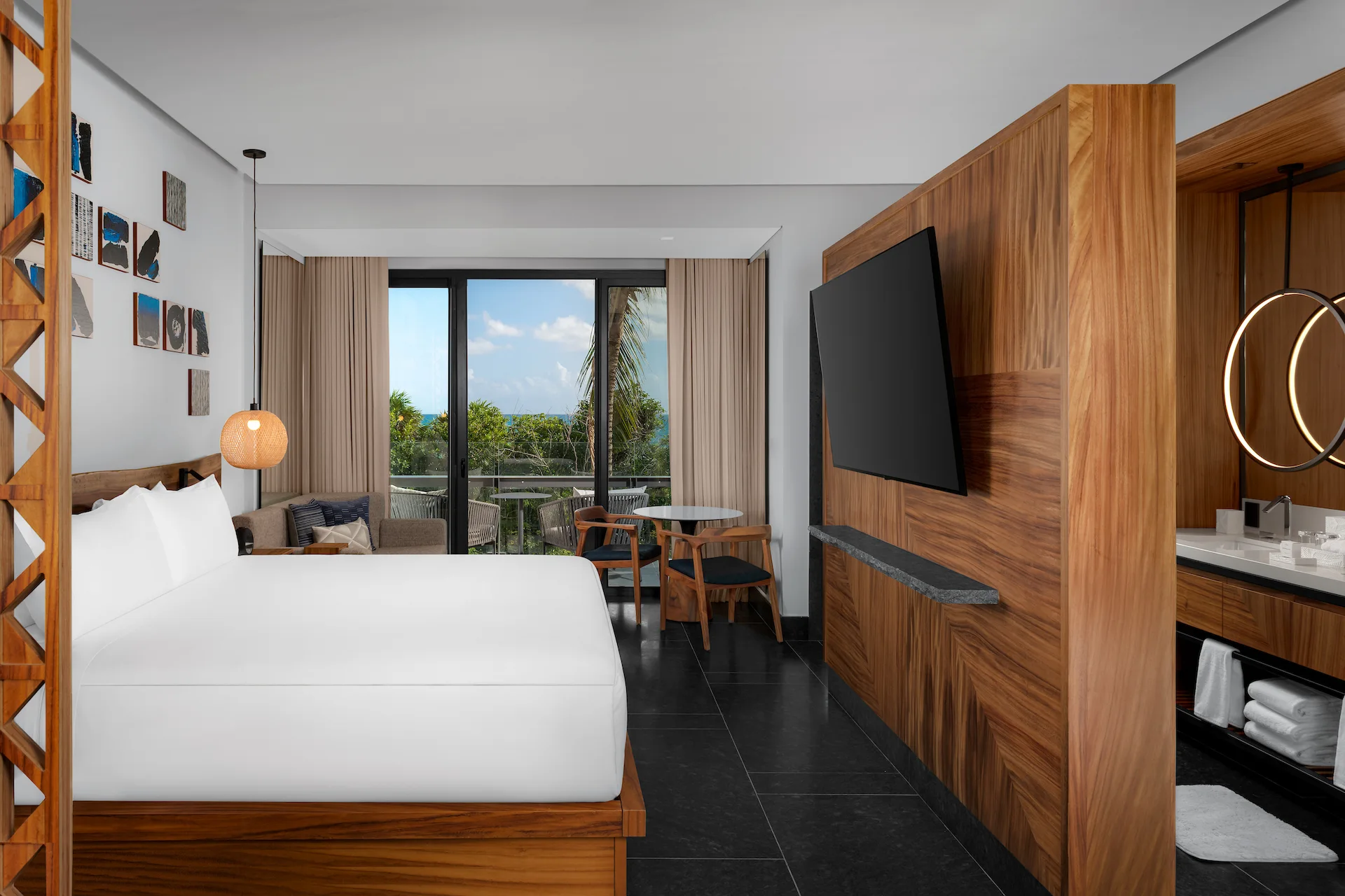 Elegant guestroom with king bed, ocean view, floor-to-ceiling windows, and private terrace at Conrad Tulum.