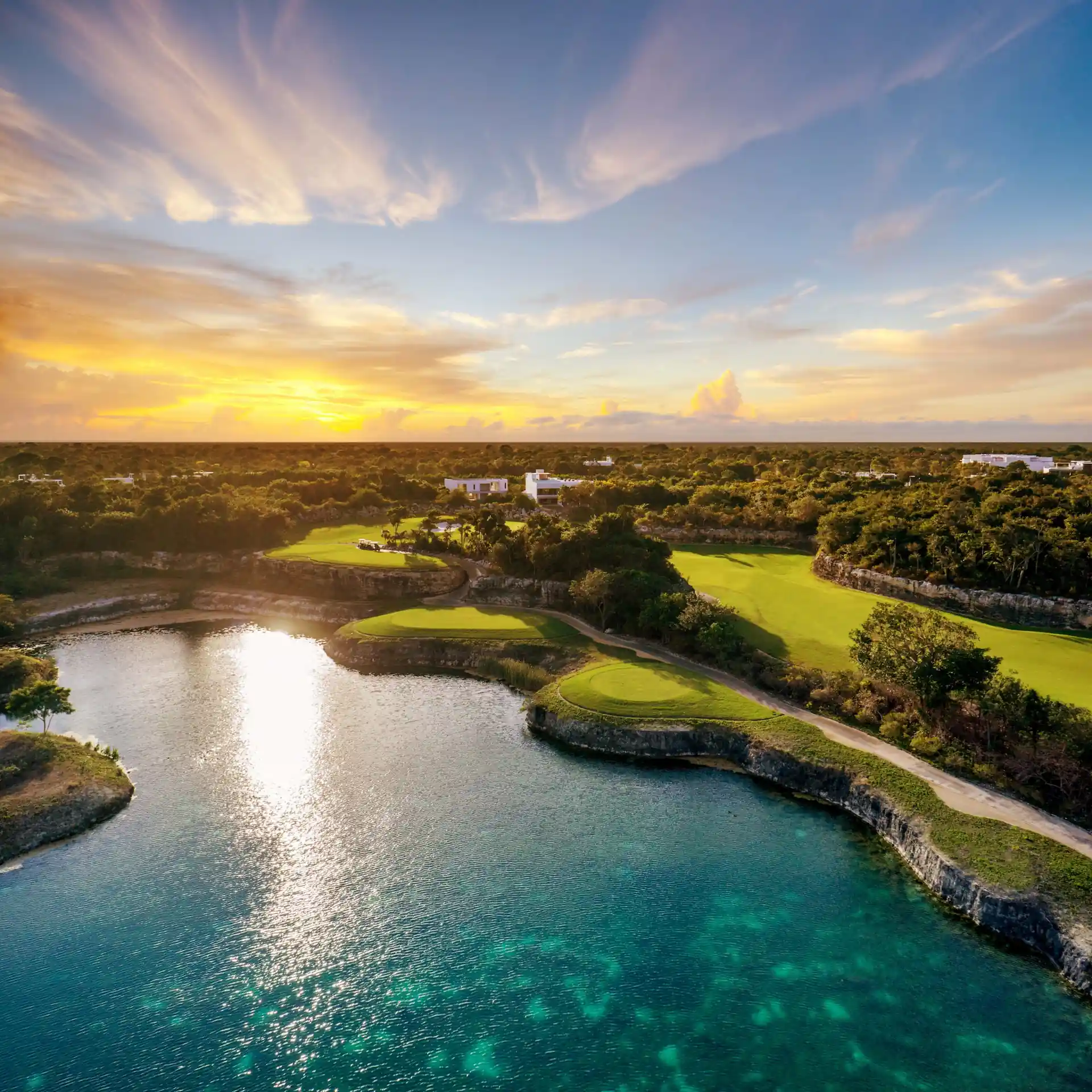 Aerial view of PGA Riviera Maya Golf Course near Conrad Tulum Riviera Maya with turquoise waters and sunset-lit fairways.