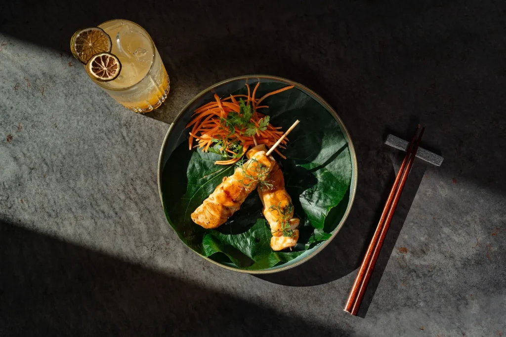 Grilled chicken skewers with herbs, julienned carrots, and citrus cocktail served at Kengai, Conrad Tulum.