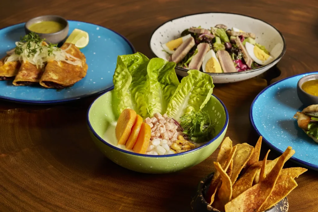 Colorful Latin dishes at ULTRAMAR, including ceviche, enchiladas, salad, tacos, and crispy chips.