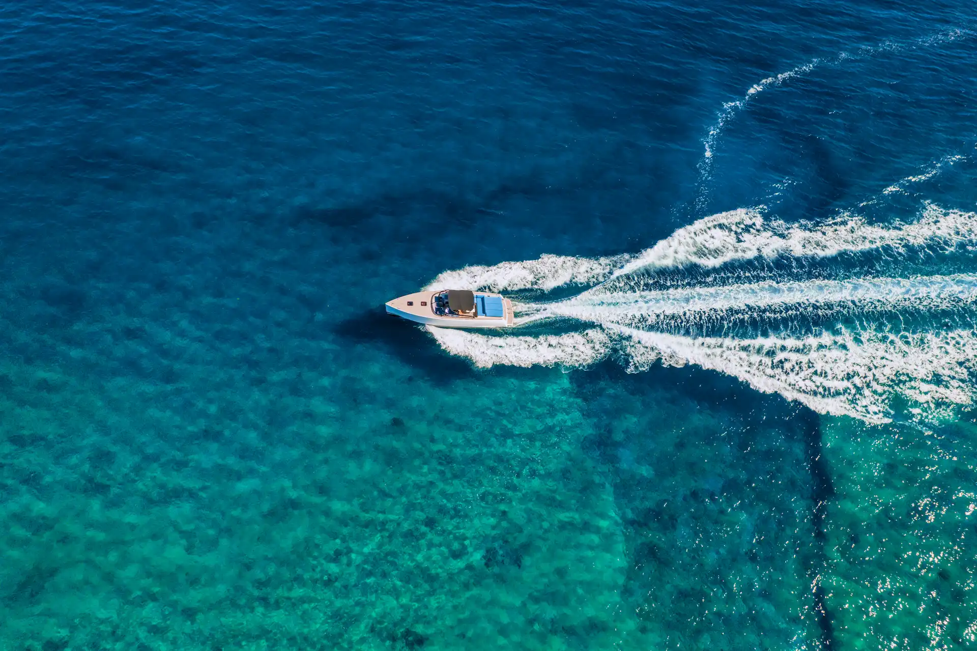 Luxury motorboat gliding through turquoise waters off the coast of Riviera Maya, leaving a crisp white wake.