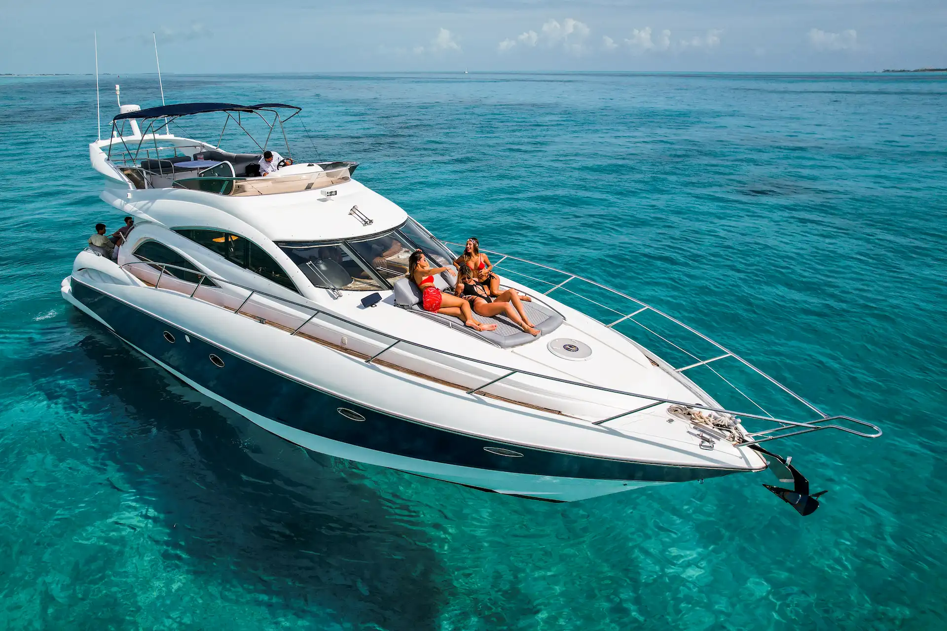 Luxury yacht floating on turquoise water with guests relaxing on deck near Riviera Maya.