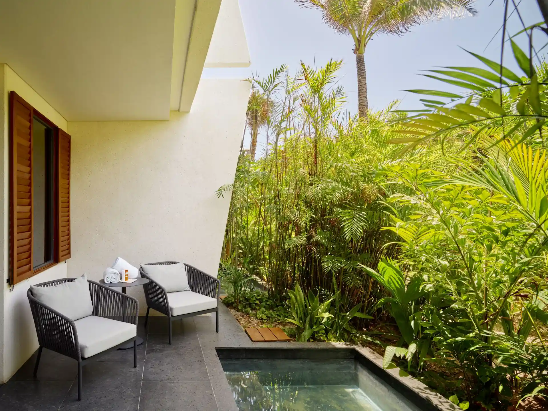 Ceiba Club Room patio at Conrad Tulum Riviera Maya with plunge pool, cushioned chairs, and tropical garden views.