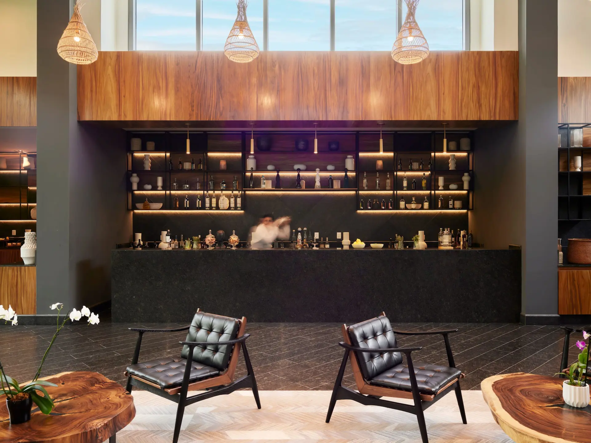 Modern Ceiba Club Lounge bar at Conrad Tulum with dark stone counters, wooden accents, and elegant leather lounge chairs.