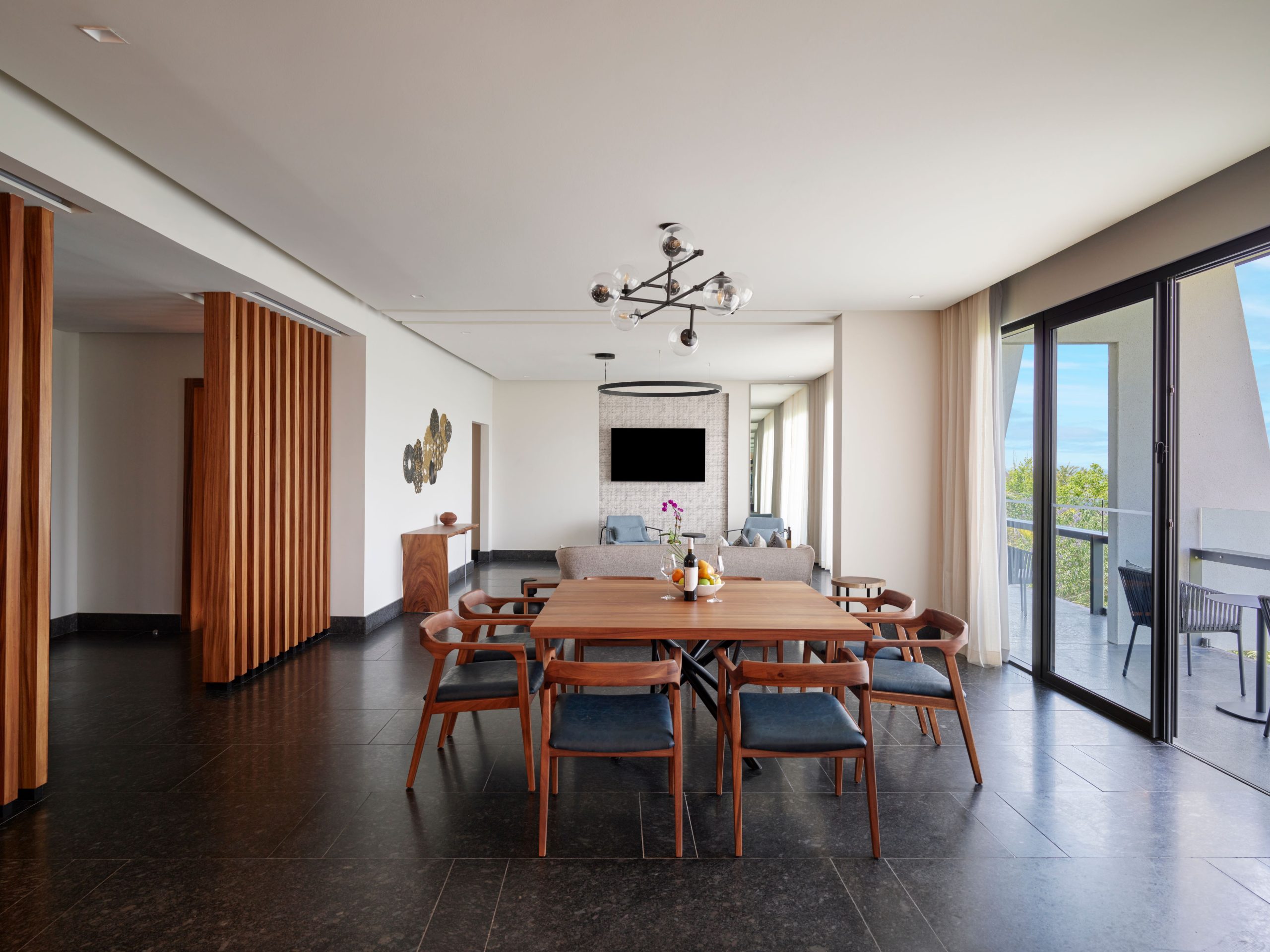 Spacious suite dining area with elegant decor, large windows, and balcony overlooking lush Tulum views.