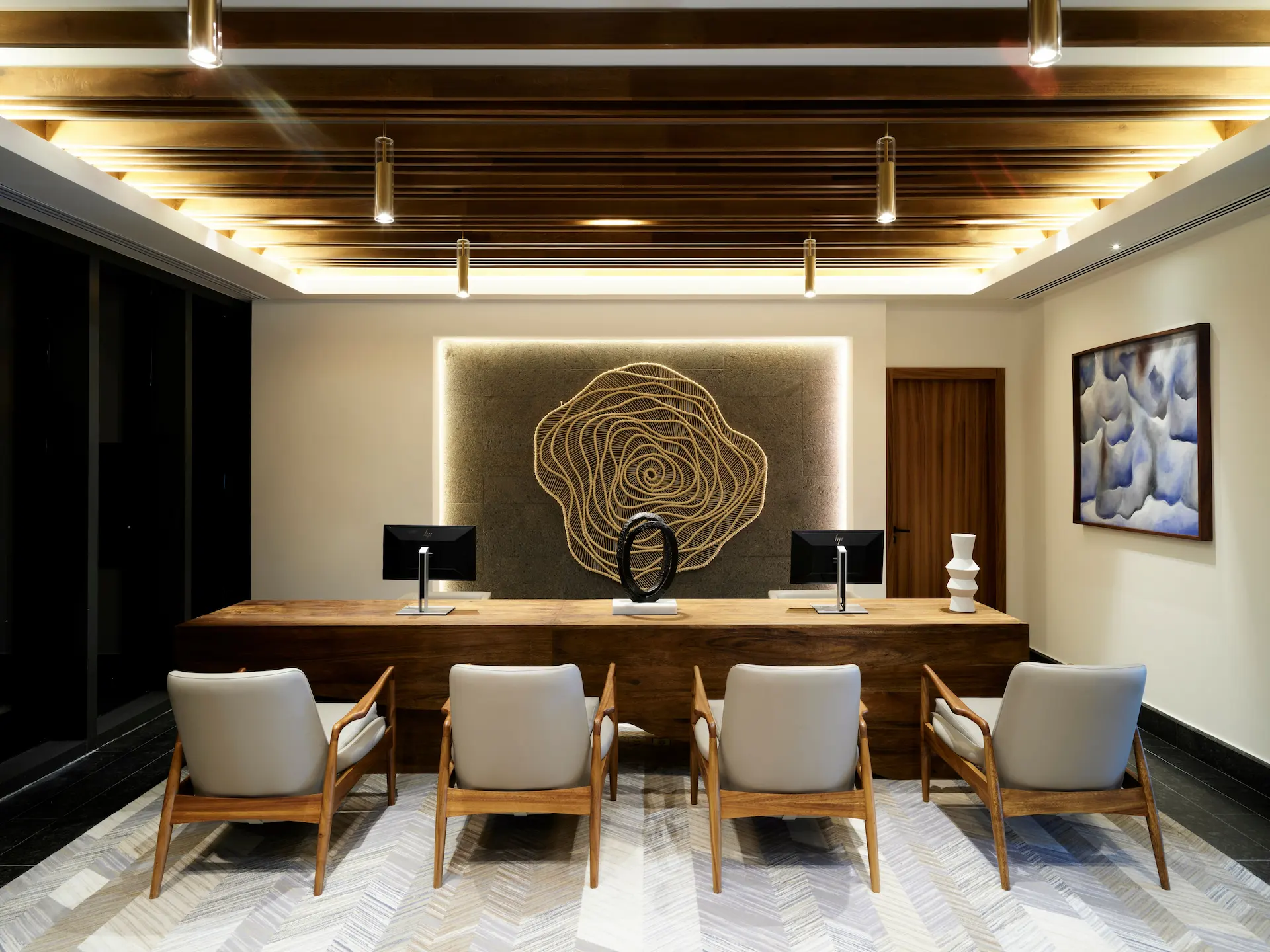 Contemporary reception area with wood accents, abstract art, and cushioned chairs in a serene resort setting.