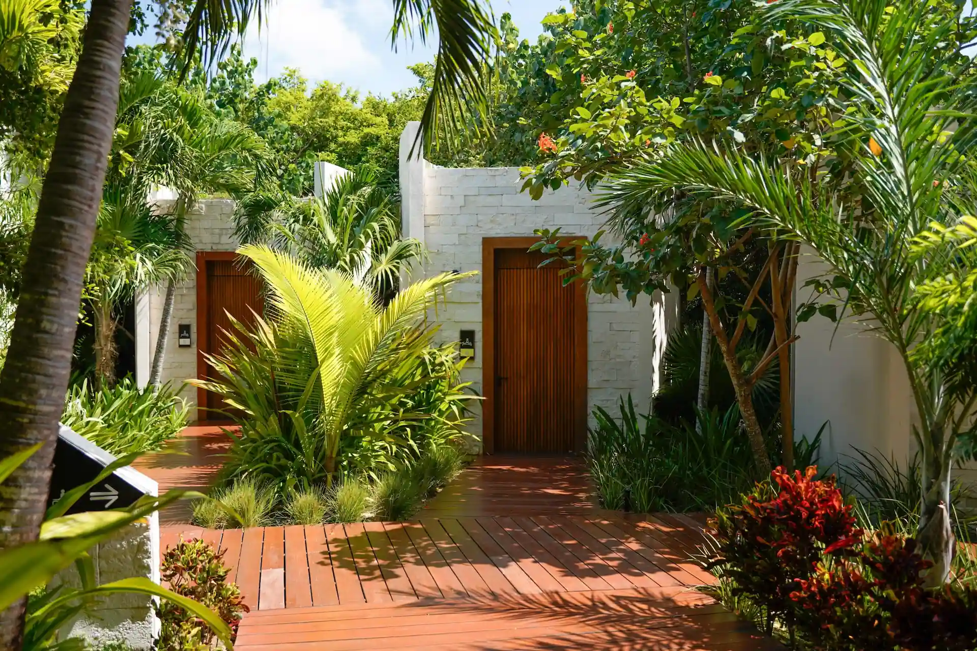 Spa entrance at Conrad Tulum Riviera Maya with tropical garden path, palm trees, and minimalist stone architecture.