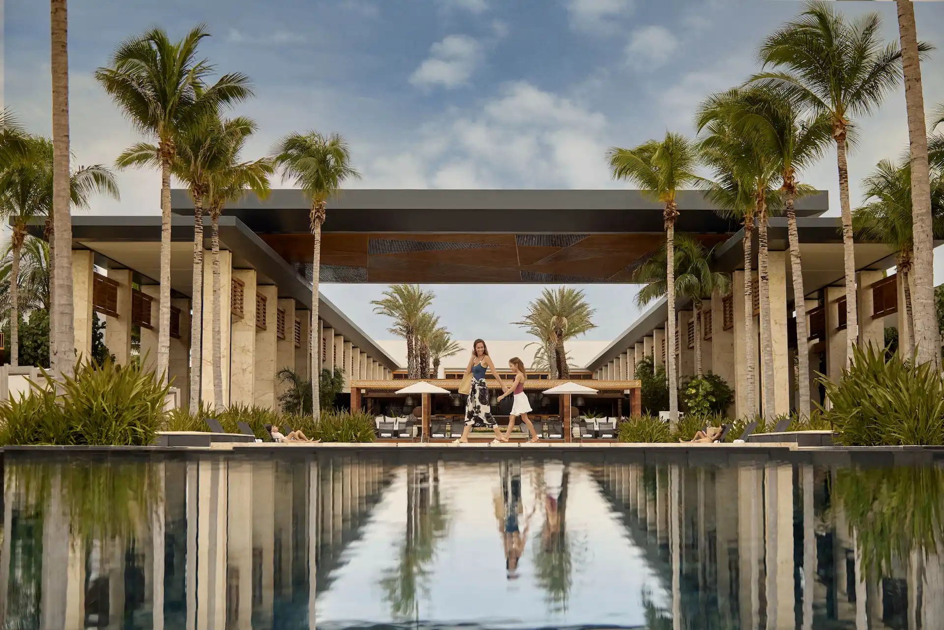 Reflective pool surrounded by palm trees & modern architecture, capturing the tranquil elegance of Conrad Tulum.