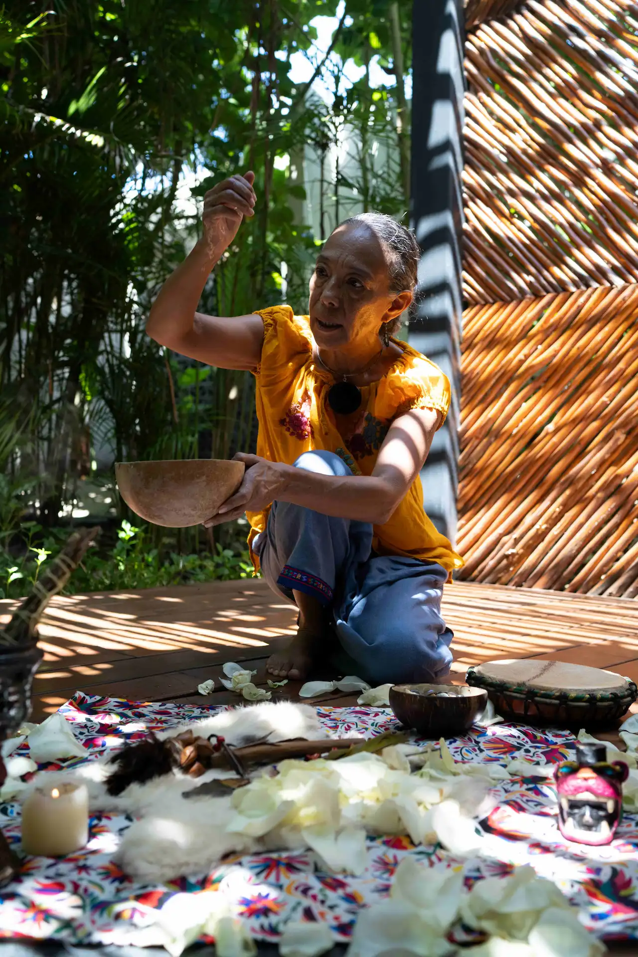 Person performing a spiritual ritual outdoors with ceremonial items on a wooden deck in Riviera Maya.