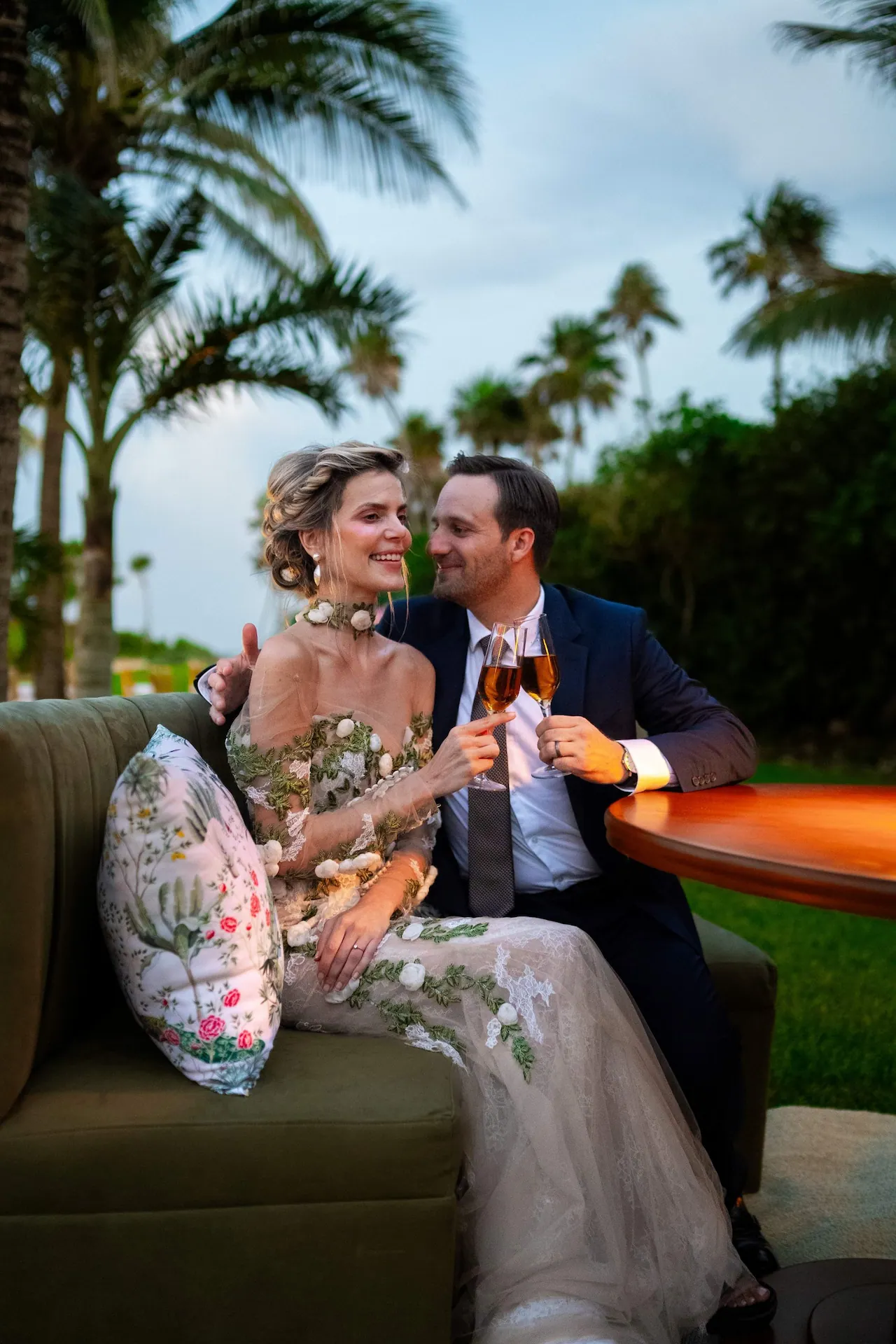 Elegant couple toasting with champagne on a garden terrace, surrounded by tropical greenery and romance.