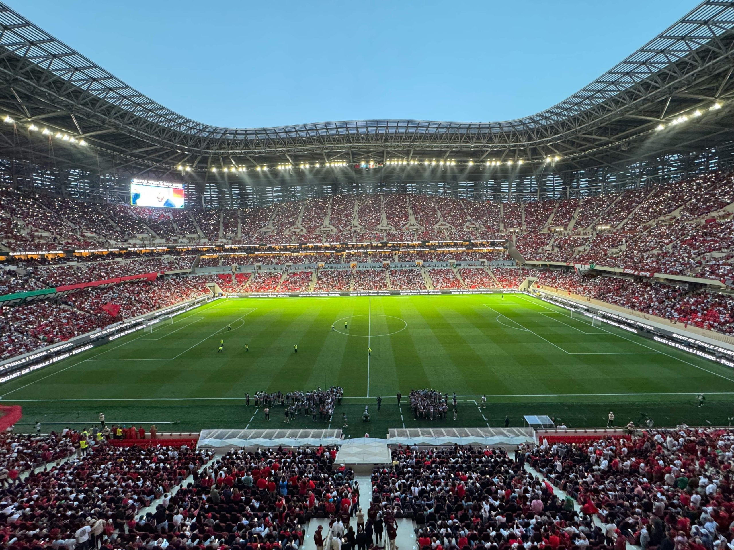 Packed football stadium filled with crowds under floodlights during a major international match.